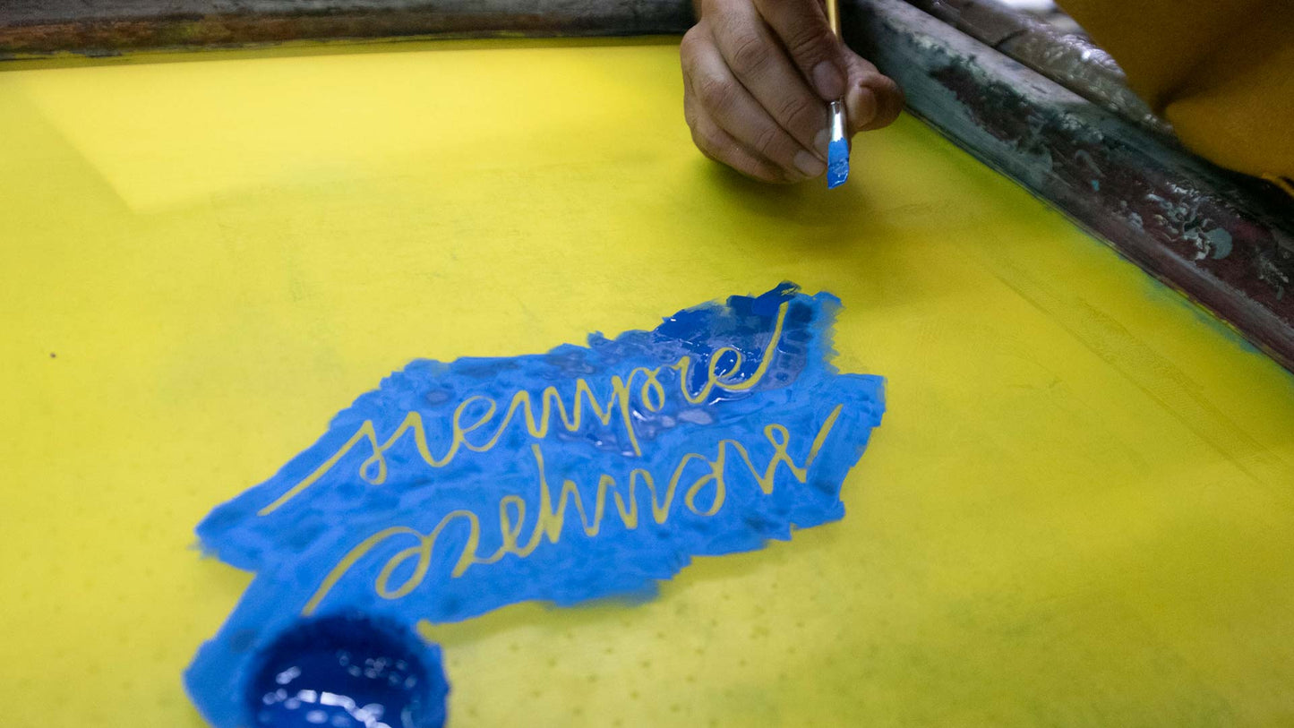 Hand writing world "siempre" on a yellow board with blue marker