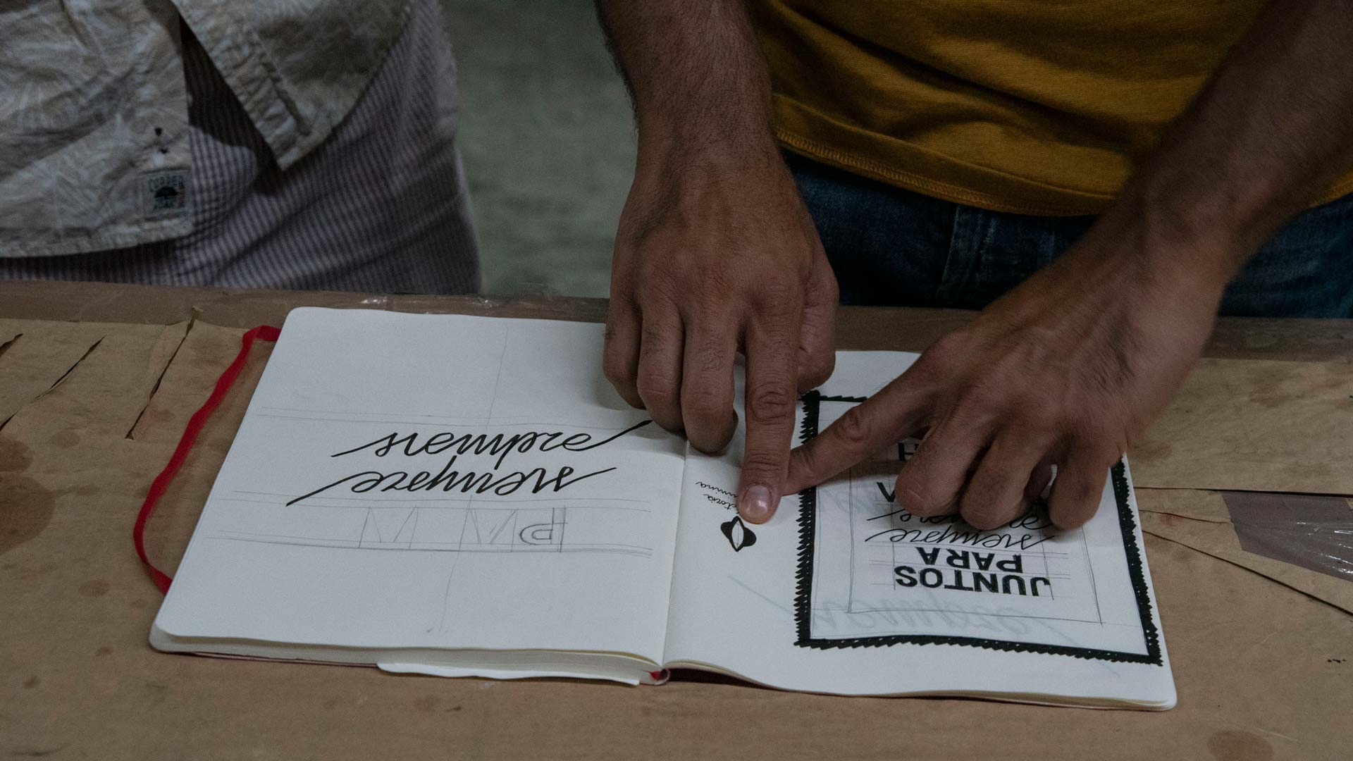 Person interacting with a notebook on a wooden surface